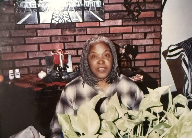 Family member seated behind a leafy plant