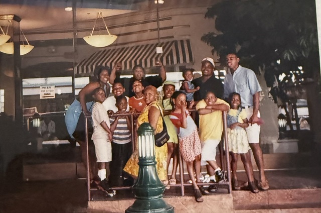 Family group posing indoors beside a railing