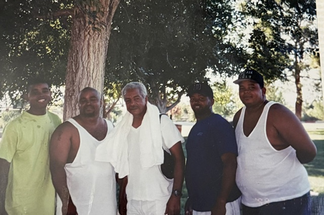 Five family members standing together under a tree