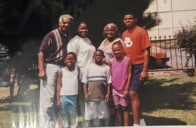 Family gathered on a lawn beside a house